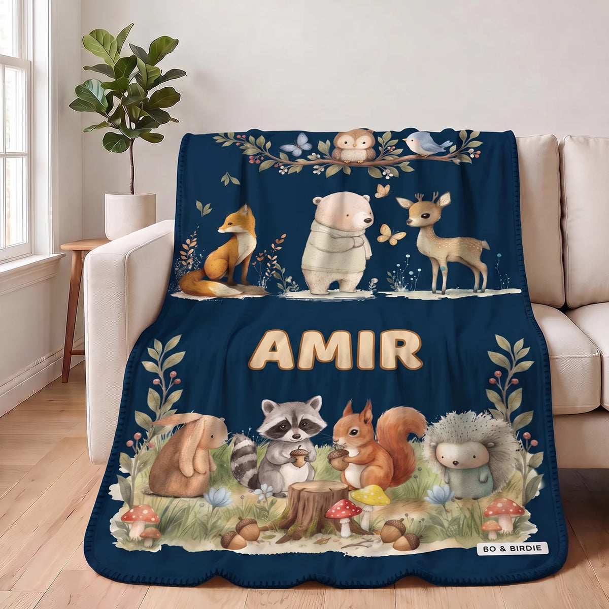 Navy Woodland Animals blanket with the name Amir draped over a sofa