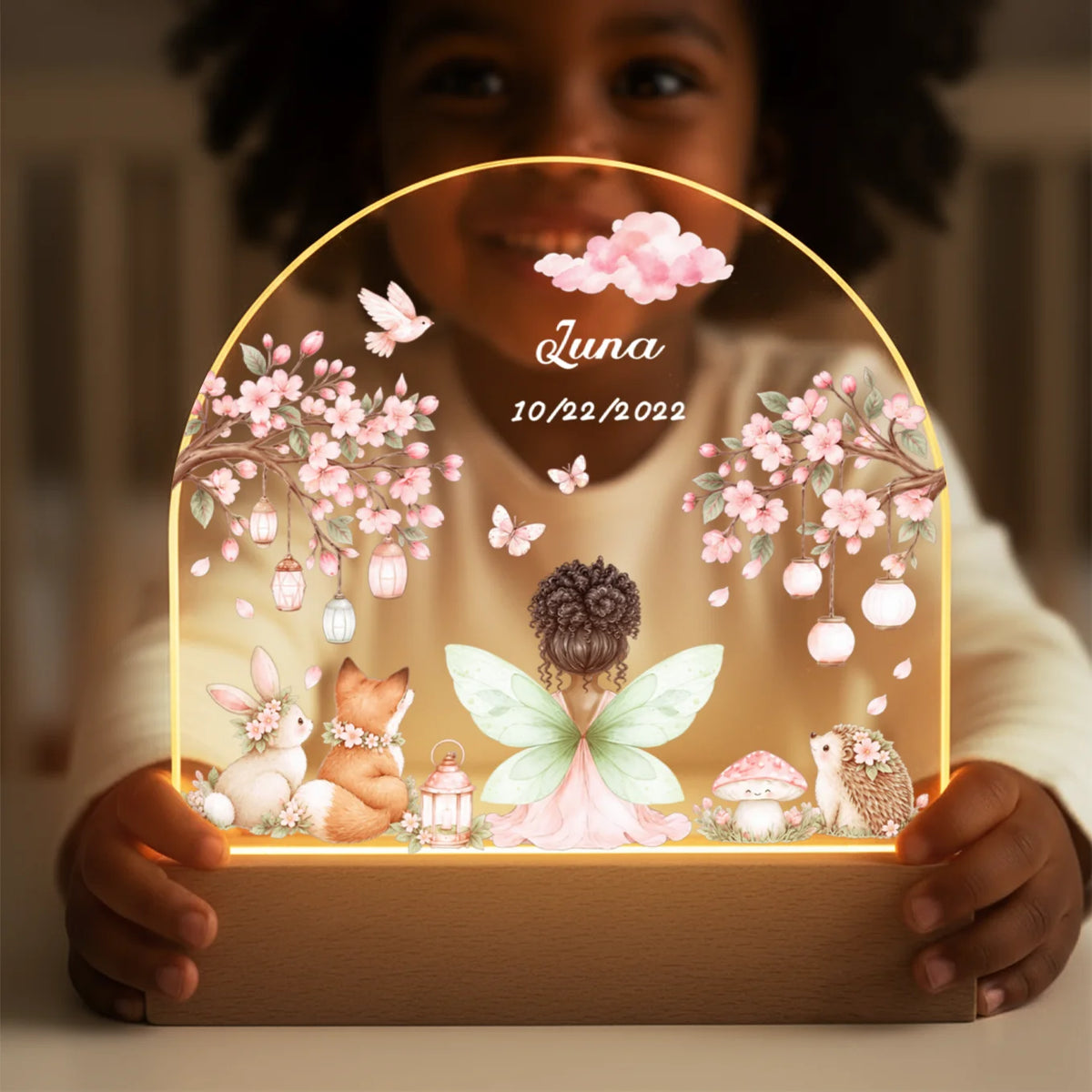 Child holds the Fairy night light with green wings, name and date in both hands
